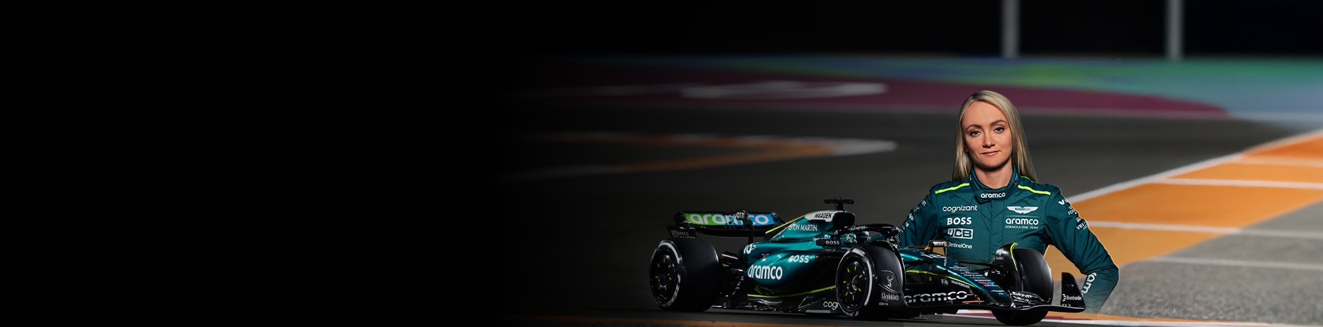 グリーンのレーシングスーツを着たドライバーとF1カーが並んでいる。