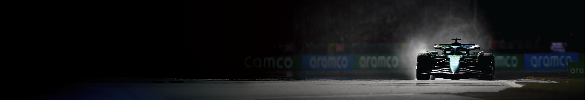 Aston Martin F1 car driving in wet conditions with dramatic lighting