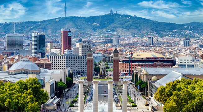 A cityscape featuring classical architecture and mountains in the background