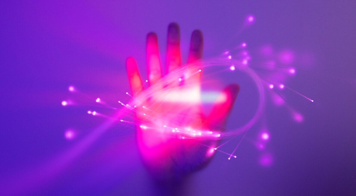 Hand with glowing fiber optic light strands.