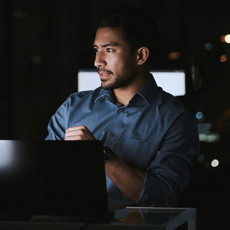 Developer working on a laptop in a low-light workspace.