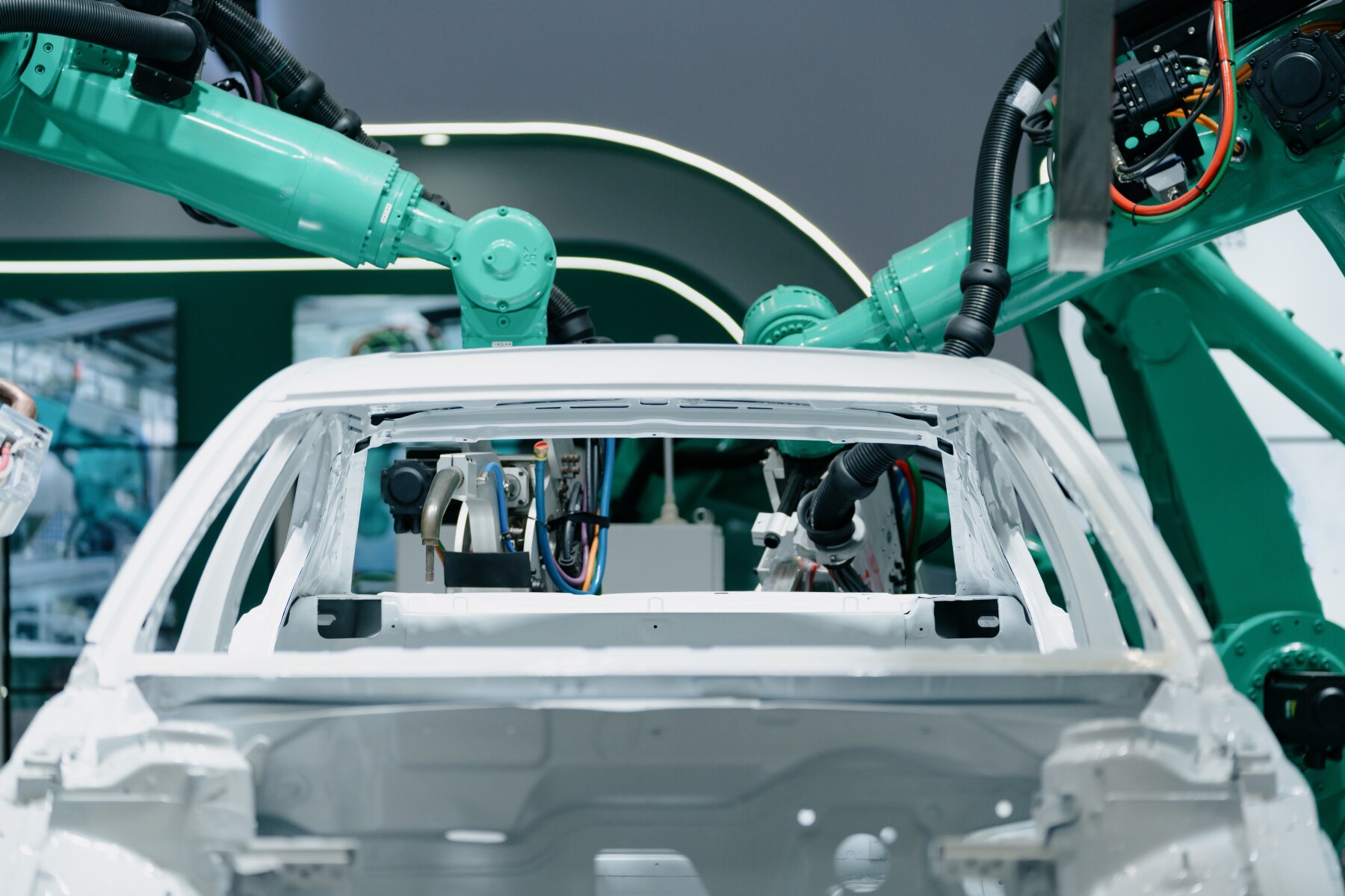 Industrial robots assembling a white car frame in an automated manufacturing facility.
