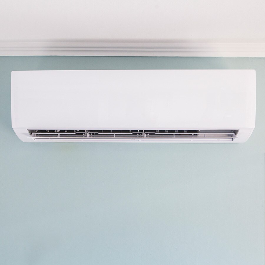 A white air conditioning unit mounted on a pastel-colored wall.