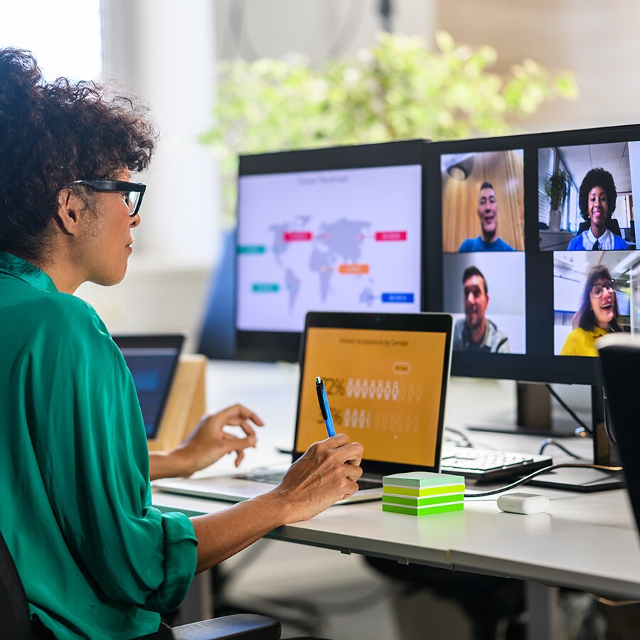 Professional woman in a video call at a multi-screen workstation.