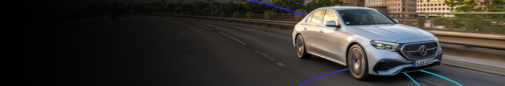 Luxury sedan driving through a city at sunset.