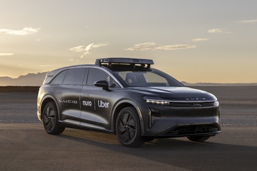 Lucid autonomous robotaxi with Arm, Nuro, and Uber logos on desert test track.