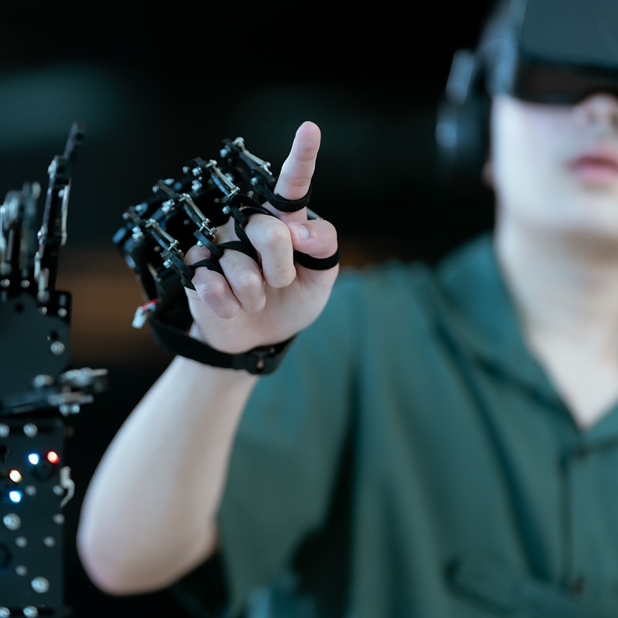 Person wearing a VR headset interacting with a robotic hand.
