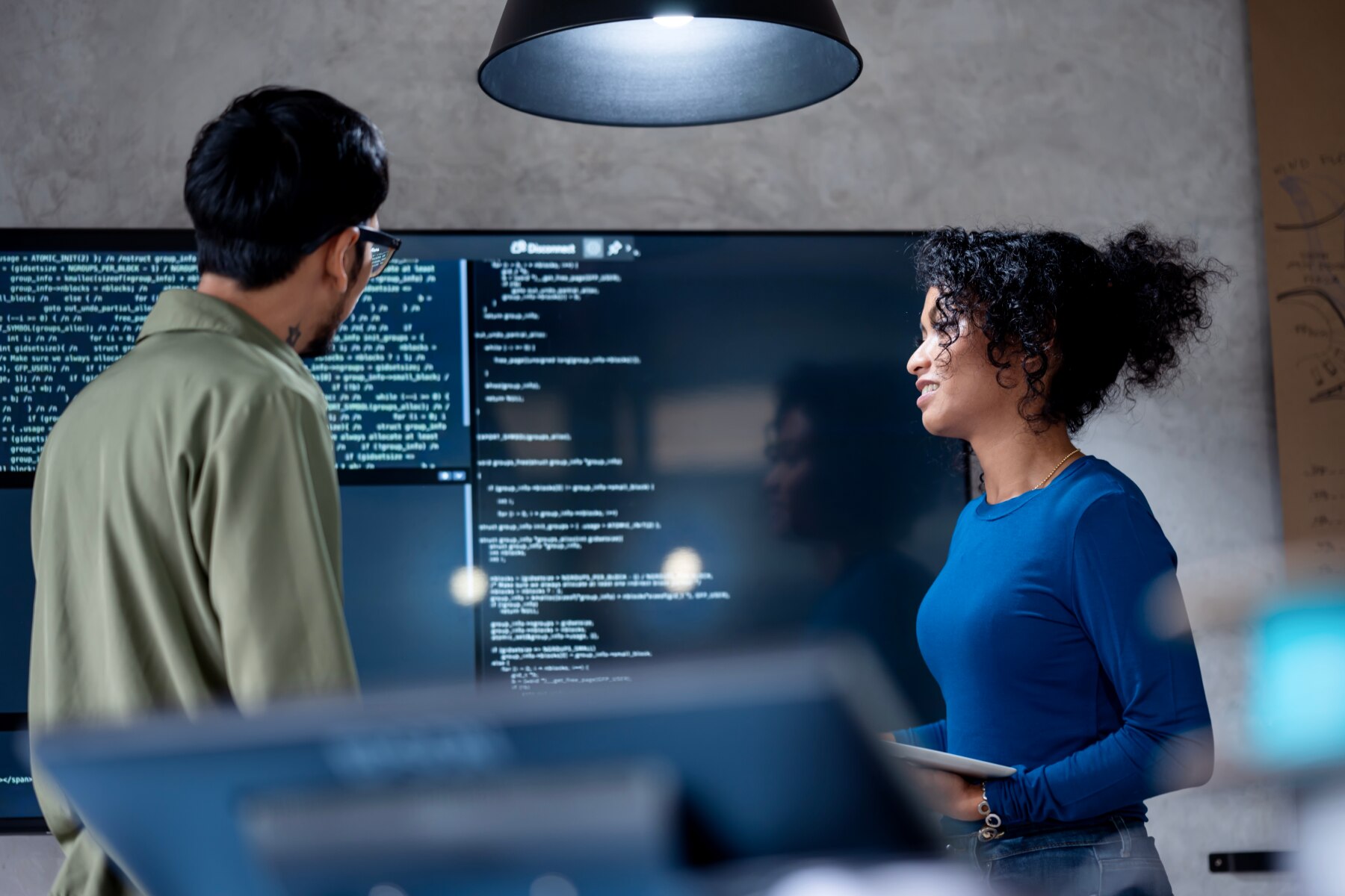 Two software engineers collaborating in front of computer screen with code.