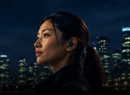 Woman wearing wireless earbud, showcasing modern audio technology and sleek wearable design.