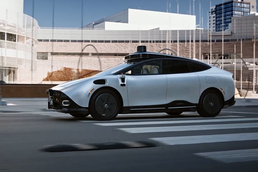 Autonomous vehicle driving past modern urban buildings.