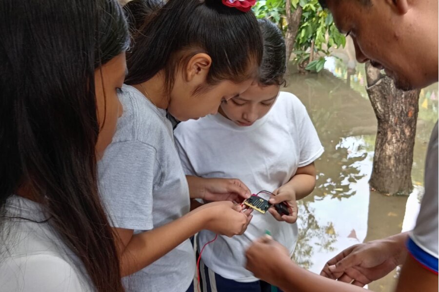 Children learning electronics outdoors with guidance.
